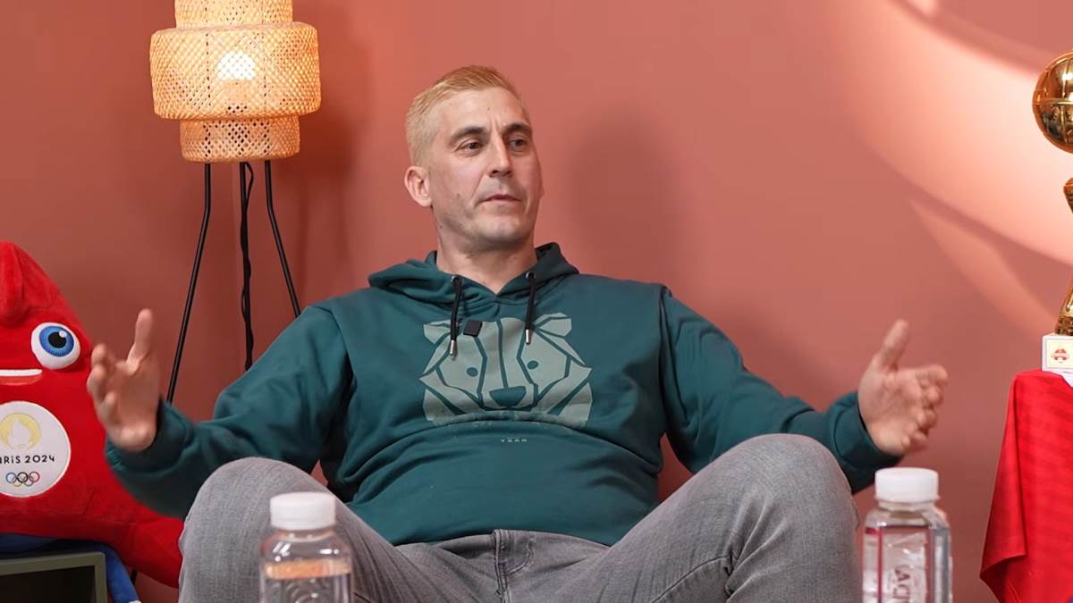 Bojan Janić sa plavom kosom širi ruke.