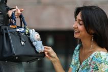 Žena rukom pipa igračku Labubu zakačenu na torbi