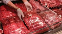 Mesar sa rukavicma odvaja deo crvenog mesa