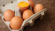 Šest jaja u kartonskoj kutiji i jedno razbijeno jaje sa žumancetom
