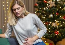 Žena se drži za stomak pored jelke