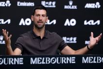 Novak Đoković raširio ruke na konferenciji za medije dok je iza njega tamna pozadina.