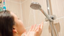 Žena u kupatilu drži ruke pod tušem