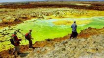 Muškarci hodaju po ivici zelenog jezera u Danakilu