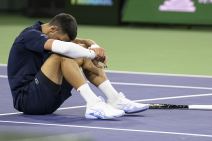 Novak Đoković sedi na betonu tužan.