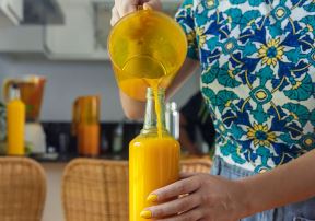 Žena sipa ceđenu pomorandžu u flašu
