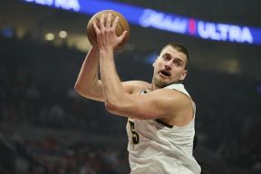 Nikola Jokić u belom dresu Denvera hvata loptu.