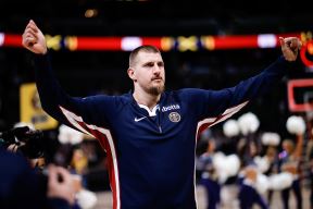 Nikola Jokić u trenerci na utakmici diže ruke.