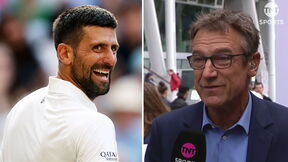 Novak Đoković u beloj majici se smeje, a Mats Vilander u plavom odelu drži mikrofon.