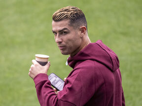 Kristijano Ronaldo pije kafu i drži telefon dok je u crvenom duksu.
