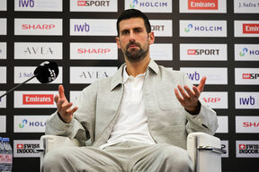 Novak Đoković u sivom odelu sedi na stolici
