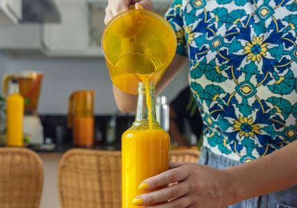 Žena sipa ceđenu pomorandžu u flašu