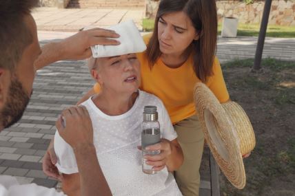 Muškarac i žena drže hladnu oblogu prolaznici kojoj se slošilo zbog vrućine