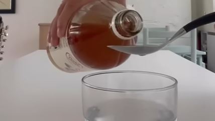 Žena sipa jabukovo sirće u kašiku