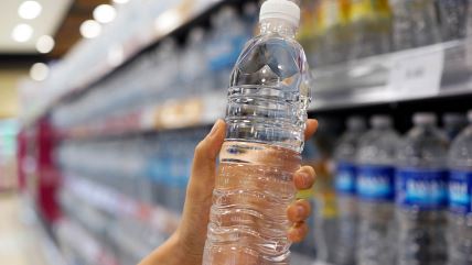 Žena drži plastičnu flašicu vode u marketu