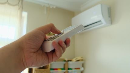 Ruka drži daljinski uperen ka klimi