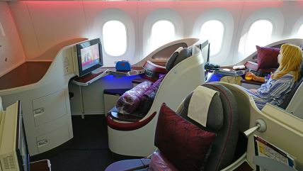 Sedišta u avionu avio-kompanije Qatar Airways i žena plave kose gleda kroz prozor.