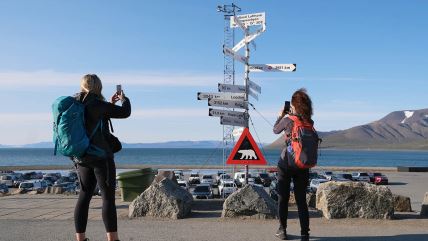 Dve žene slikaju putokaze u Svalbard između Norverške i Severnog pola.