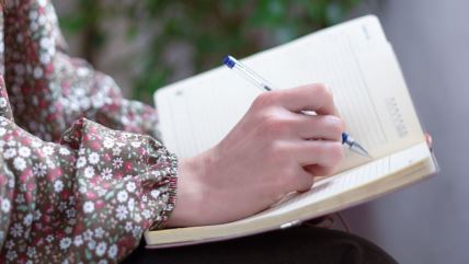 Ruka drži olovku nad sveskom