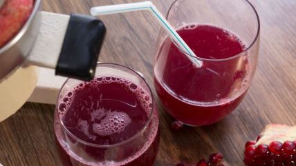 Sveže ceđen sok od nara u čašama i zrna nara na stolu.