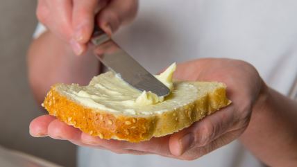 Margarina se razmazuje po kriški hleba od kiselog testa