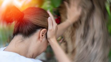 Žena drži ruke na glavi, oseća glavobolju i vrtoglavicu