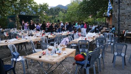 Stolovi i ljudi koji slave na Ikariji u Grčkoj