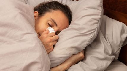 Žena briše nos dok leži u krevetu
