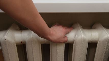 Ruka na radijatoru ispod prozora