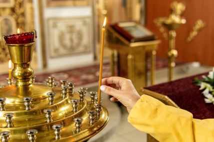 Žena pali sveću u crkvi