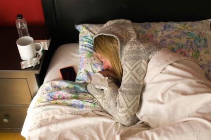 Žena leži u krevetu sa maramicom u rukama