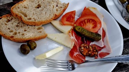 Hleb, sir, masline, paradajz, krastavac i suhomesnato na belom tanjiru