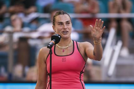 Arina Sabalenka diže ruku i obraća se publici.