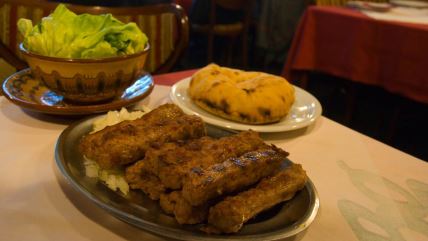 Ćevapi sa lukom, lepinja i zelena salata na stolu