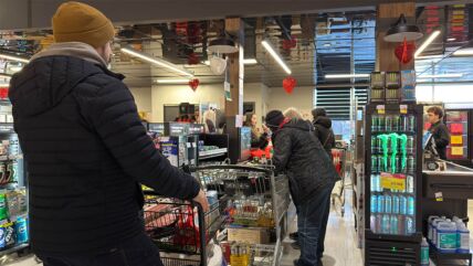 Ljudi stoje u redu na kasi u marketu