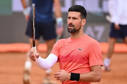Novak Đoković u narandžastoj majici i sa belim rukavom.