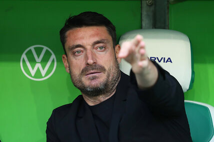 Albert Rijera sedi na klupi i rukom pokazuje dok je iza njega zelena pozadina.
