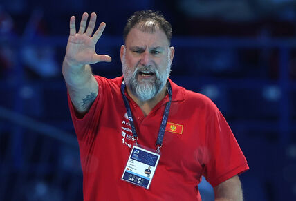 Dejan Savić diže ruku u crvenoj majici.
