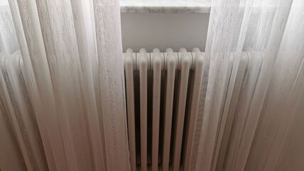 Radijator iza bele zavese