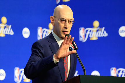 Adam Silver pokazuje rukom tokom obraćanja za govornicom.