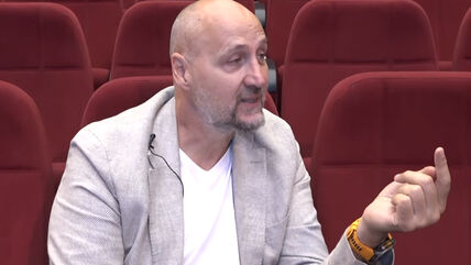Dino Rađa na TV E daje intervju dok sedi na crvenim stolicama.