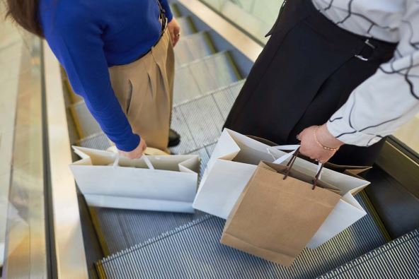 Žene drže kese u rukama na pokretnim stepenicama