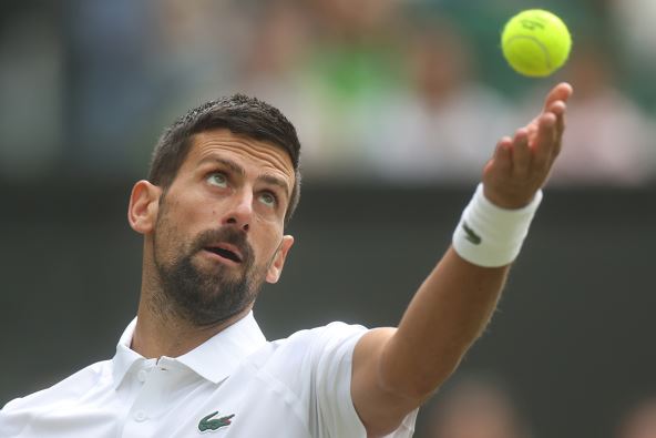 Novak Đoković baca lopticu i servira na Vimbldonu.