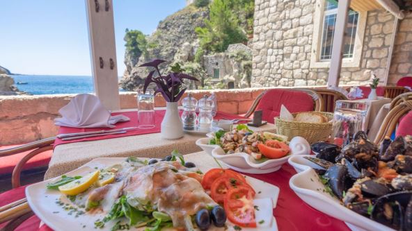 Morski plodovi u tanjirima na stolu restorana sa pogledom na more