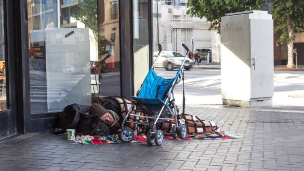 Beskućnik leži na ulici Los Anđelesa u Kaliforniji, na ćebetu pored dečijih kolica