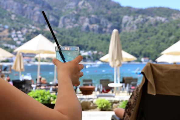 Mladić drži čašu hladne vode sa slamčicom na plaži u Turskoj