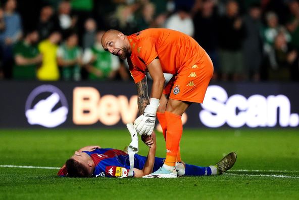 Marko Milošević sa fudbalerom Partizana koji leži na zemlji.