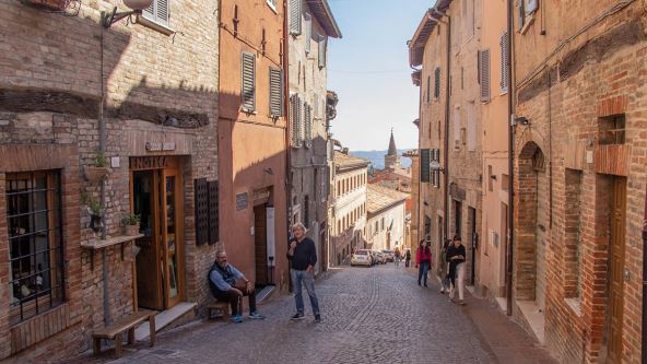 Muškarac sedi dok žena stoji u ulici u Italiji