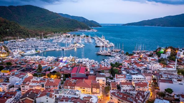 Pogled iz vazduha na luku Marmarisa sa jahtama i jedrilicama u večernjem osvetljenju.