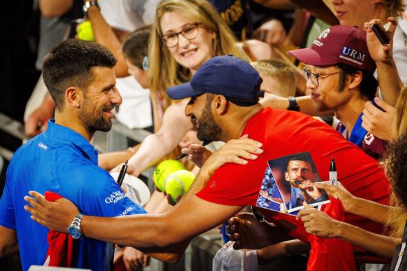 Novak Đoković u zagrljaju s navijačem u crvenoj majici.